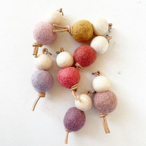 Bolas de fieltro de colores y cuentas de madera en una cuerda.
