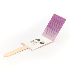 Un kit de plantación con palos de madera, paquetes de semillas e instrucciones desplegadas en cartón violeta.