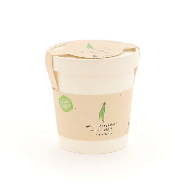 Una taza blanca con una etiqueta beige que representa un guisante verde y la frase "No me importa... el guisante".