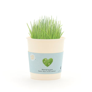 Taza con césped verde y una banderilla que representa un corazón verde y el texto “No se puede cortar un corazón que corre”.