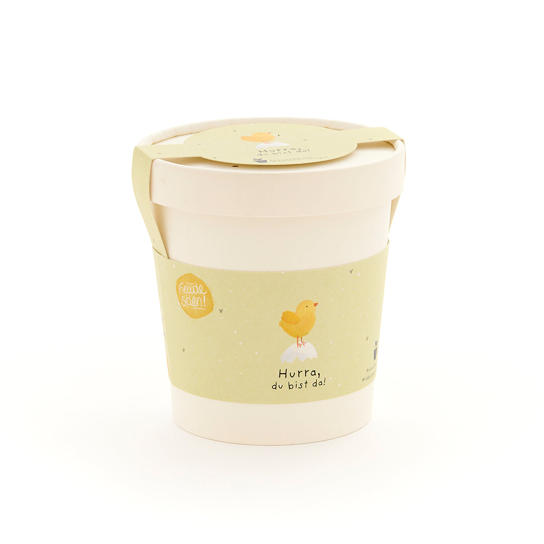 Taza con etiqueta amarilla que representa un pollito y la inscripción "¡Hurra, estás aquí!"