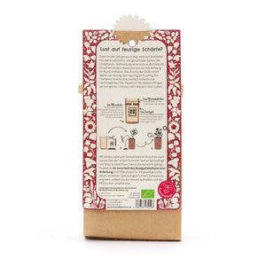 Parte posterior de un paquete con instrucciones para plantar chile, rodeado de un patrón floral rojo, con texto e ilustraciones en alemán.