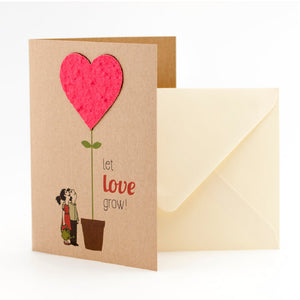 Tarjeta de felicitación con motivo de corazón y el texto "¡Deja que el amor crezca!", al lado un sobre.