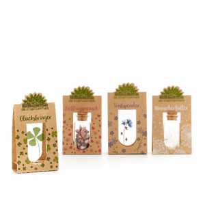 Cuatro pequeñas bolsas de regalo etiquetadas como "Amuleto de la suerte", "Persona favorita", "Consolador" y "Concededor de deseos", cada una con diferentes motivos vegetales.