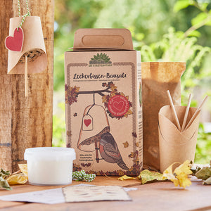Embalaje de un kit de golosinas para pájaros con campana de alimentación y decoración natural de fondo.