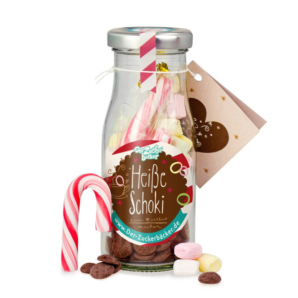 Botella de leche etiquetada como "Chocolate caliente" y dulces como malvaviscos, galletas de chocolate y bastones de caramelo.