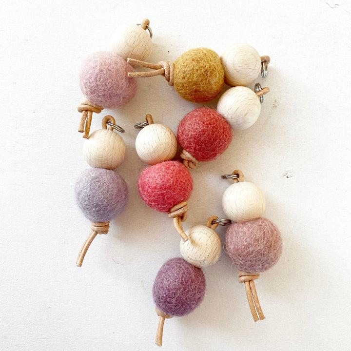Bolas de fieltro de colores y cuentas de madera en una cuerda.