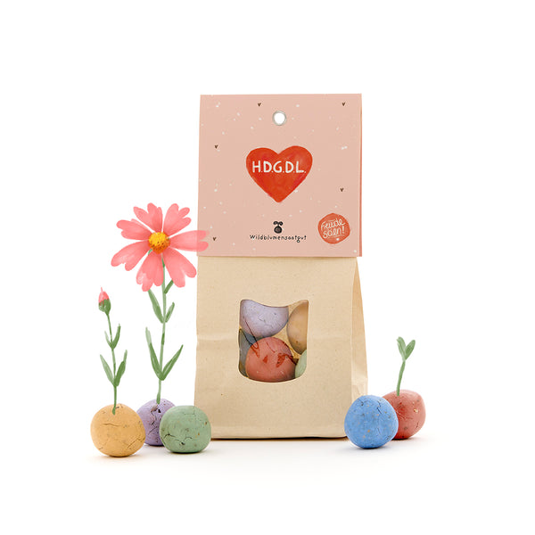 Pack de bombas de semillas y flores silvestres formadas por bolas de colores, algunas ya brotando, con etiqueta rosa "HDGDL".