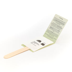 Palitos de madera con paquetes de semillas e instrucciones ilustradas en alemán.