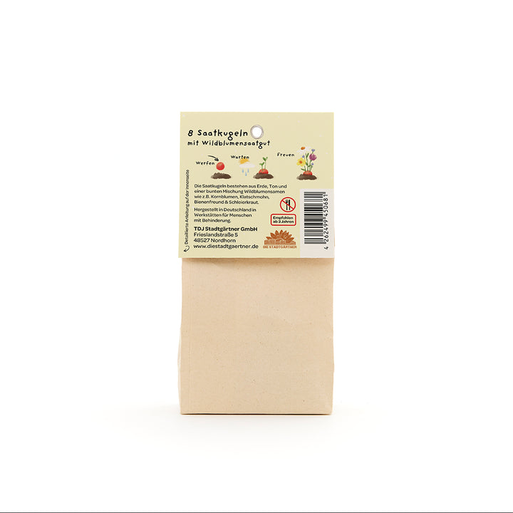 Bolsa de papel marrón con una etiqueta que dice "8 bolas de semillas con semillas de flores silvestres", junto con ilustraciones e información del producto en alemán.