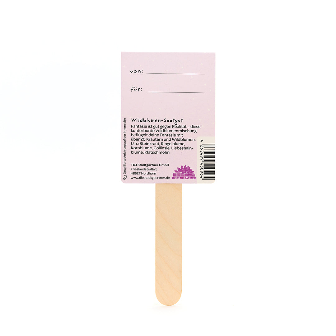 Palitos de madera con una etiqueta rosa que dice "von" y "für" y proporciona información sobre semillas de flores silvestres en alemán.