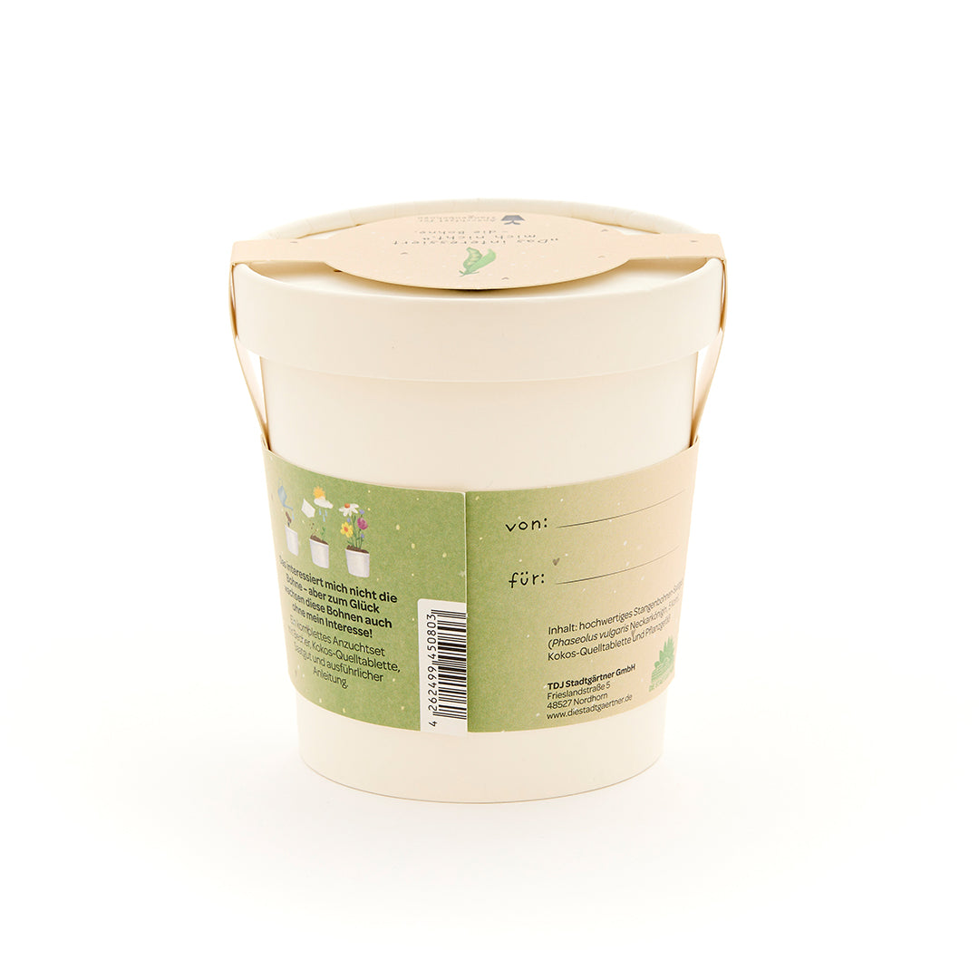 Maceta beige con etiqueta verde, campos de texto "de:" y "para:", y descripción y dibujos de plantas en la parte posterior.