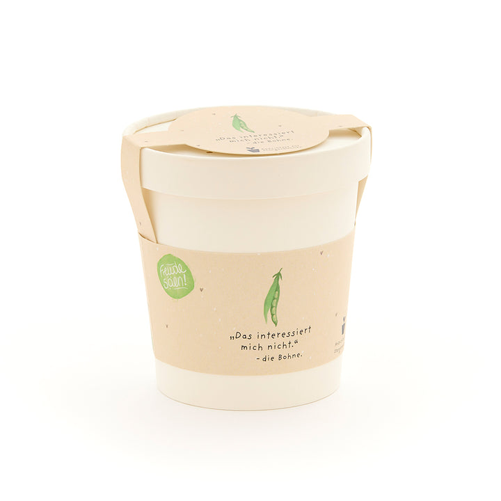 Una taza blanca con una etiqueta beige que representa un guisante verde y la frase "No me importa... el guisante".