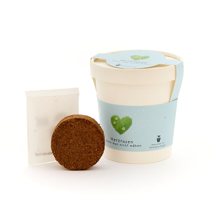 Kit de cultivo con vaso blanco, tierra y paquete de semillas, con etiqueta azul "Heart Rasen".