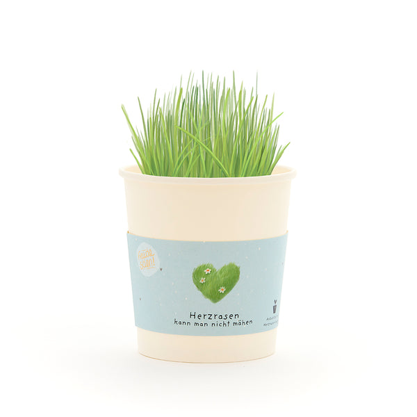 Taza con césped verde y una banderilla que representa un corazón verde y el texto “No se puede cortar un corazón que corre”.