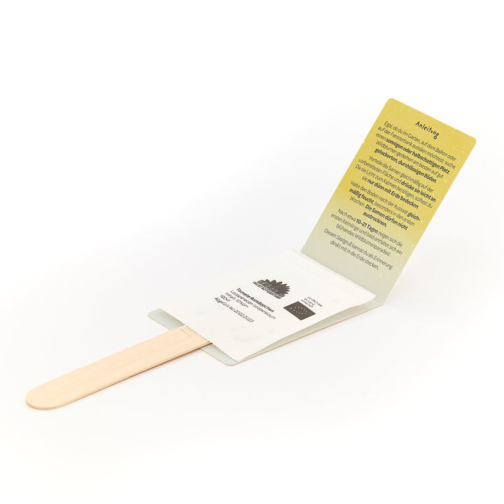 Juego de semillas con palitos de madera y embalaje desplegable con instrucciones en alemán.
