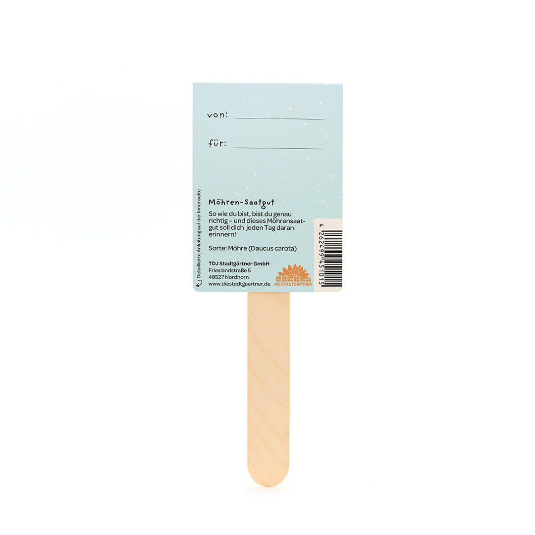Parte posterior de una etiqueta de semillas de zanahoria en un palo de madera con campos para "de" y "para" e información sobre las semillas de zanahoria en alemán.