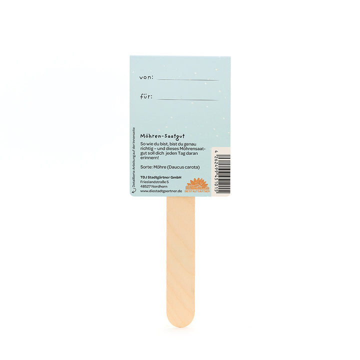 Parte posterior de una etiqueta de semillas de zanahoria en un palo de madera con campos para "de" y "para" e información sobre las semillas de zanahoria en alemán.