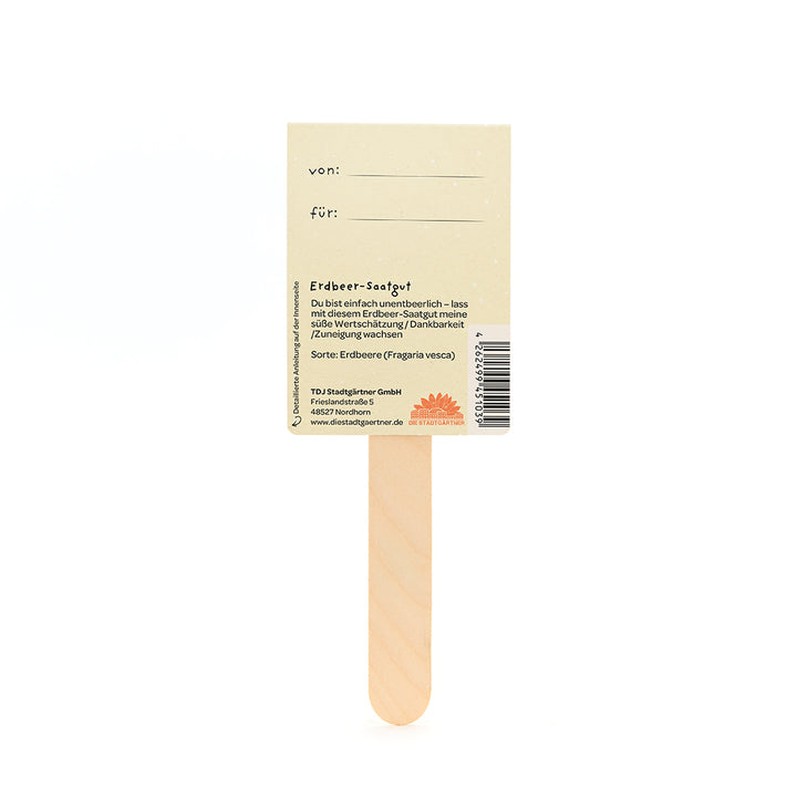 Parte posterior de una etiqueta de semillas de fresa en un palo de madera, con campos para "de" y "para" y una descripción de la semilla en alemán.