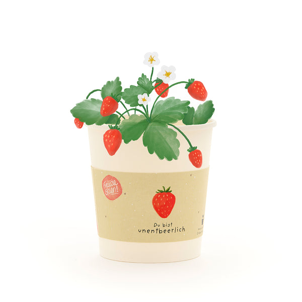 Una maceta de color crema con el dibujo de una planta de fresa, fresas rojas y flores blancas, así como la inscripción "Eres indispensable".