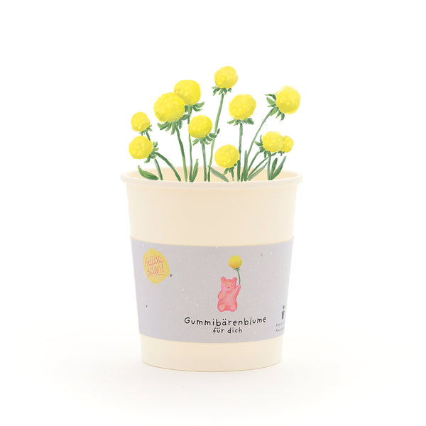 Taza con flores de gomita de color amarillo y una etiqueta que dice “Flor de gomita de osito para ti”.