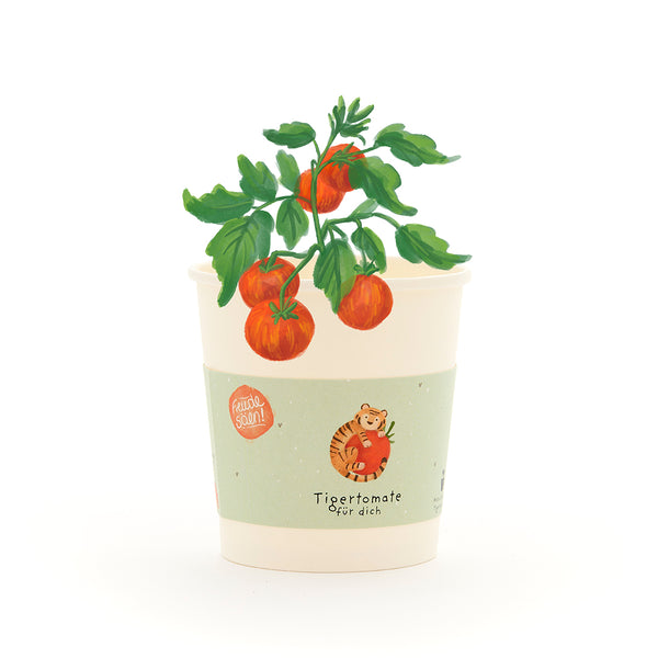 Taza con una pequeña planta de tomate, la etiqueta dice “Tomate tigre para ti” y muestra un dibujo de un tigre con un tomate.