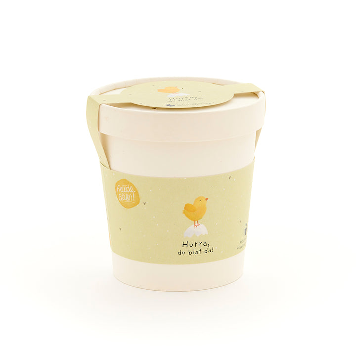 Taza con etiqueta amarilla que representa un pollito y la inscripción "¡Hurra, estás aquí!"