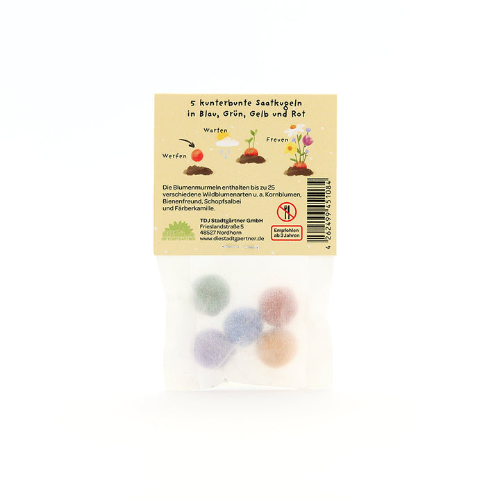 Cinco bolas de semillas de colores en un paquete transparente con instrucciones e ilustraciones en alemán en la parte posterior.