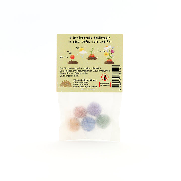 Cinco bolas de semillas de colores en una bolsa transparente con embalaje beige e instrucciones en alemán para flores silvestres.