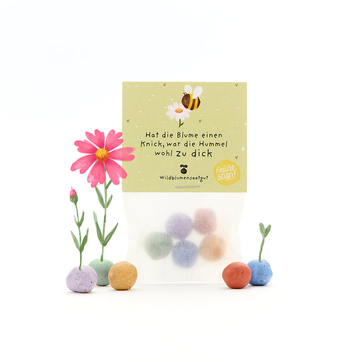 Una bolsa con bolas de semillas de colores, algunas flores florecientes y una etiqueta con una abeja y el dicho: "Si la flor está doblada, el abejorro probablemente estaba demasiado gordo".