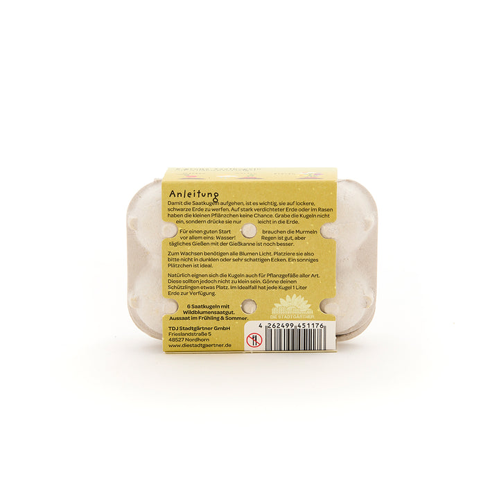 Parte posterior de un pequeño cartón de huevos con instrucciones adjuntas para sembrar semillas, código de barras e información del fabricante en alemán.