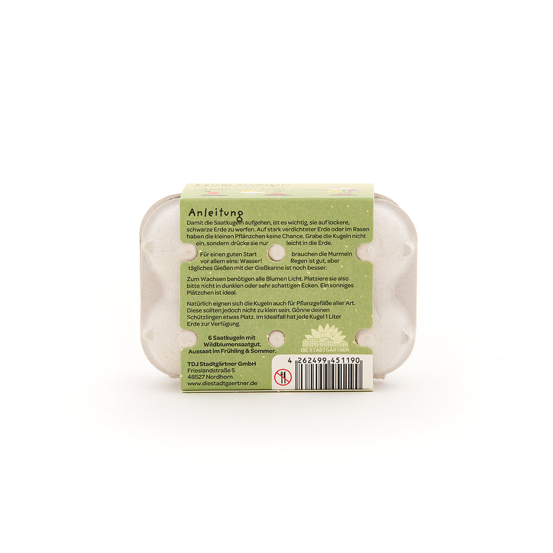 Parte posterior de un paquete con instrucciones verdes para utilizar bolas de semillas, incluido un código de barras e información de contacto del fabricante.