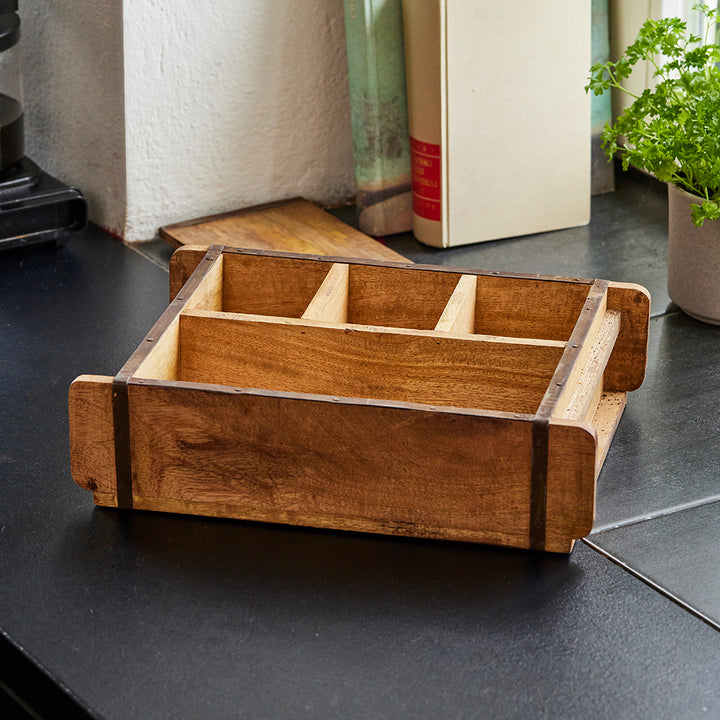 Inserto de cajón de madera con múltiples compartimentos sobre encimera de cocina negra.