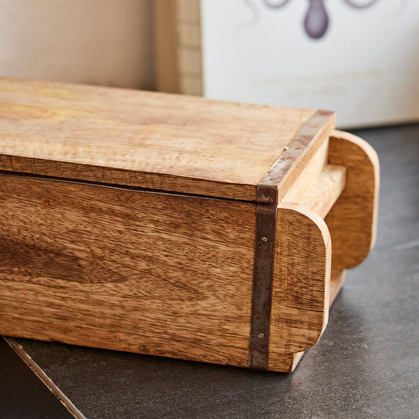 Caja rectangular de madera con refuerzos metálicos sobre superficie oscura.