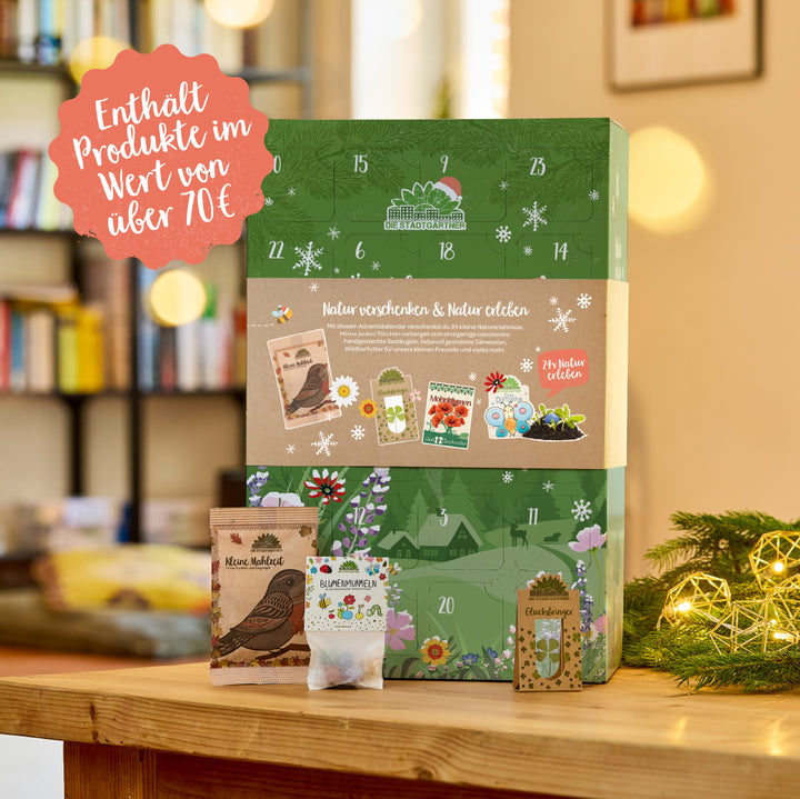 Sobre una mesa de madera hay un calendario de Adviento con un diseño verde e invernal, frente a una estantería borrosa, con adornos y pequeñas bolsas para semillas y bolas de flores en primer plano; el texto en el calendario y una burbuja roja indican productos con un valor superior a 70 euros.
