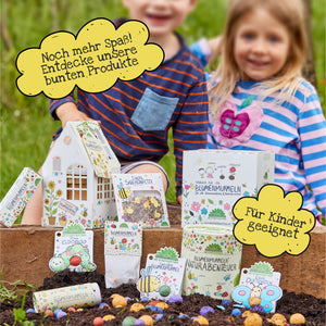 Dos niños sonrientes con bolsas de semillas de colores en el jardín, rodeados de bocadillos con el texto "¡Más diversión aún! Descubre nuestros productos coloridos" y "Apto para niños".