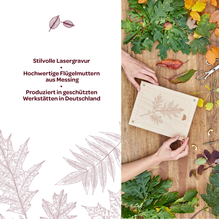 Dos manos sostienen una placa de madera con un delicado grabado láser de una hoja, rodeada de varias hojas de otoño coloridas y materiales de artesanía; junto a ella hay un texto con información sobre el grabado láser, tuercas de mariposa de latón y producción en Alemania.