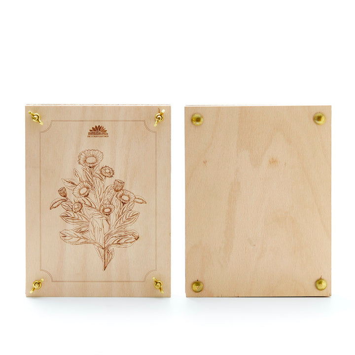 Dos placas de madera, una con grabado floral y tornillos de latón, la otra sin decorar.