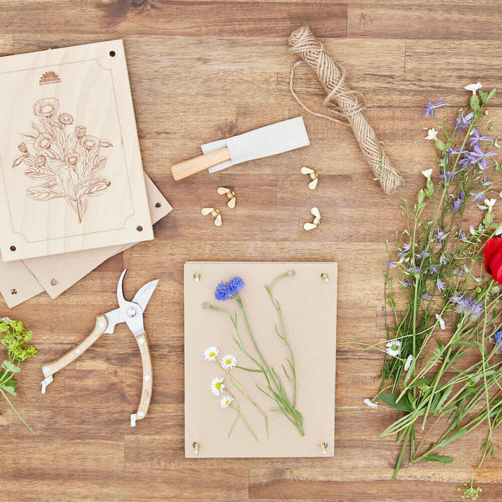 Materiales de artesanía y flores prensadas sobre una mesa de madera.