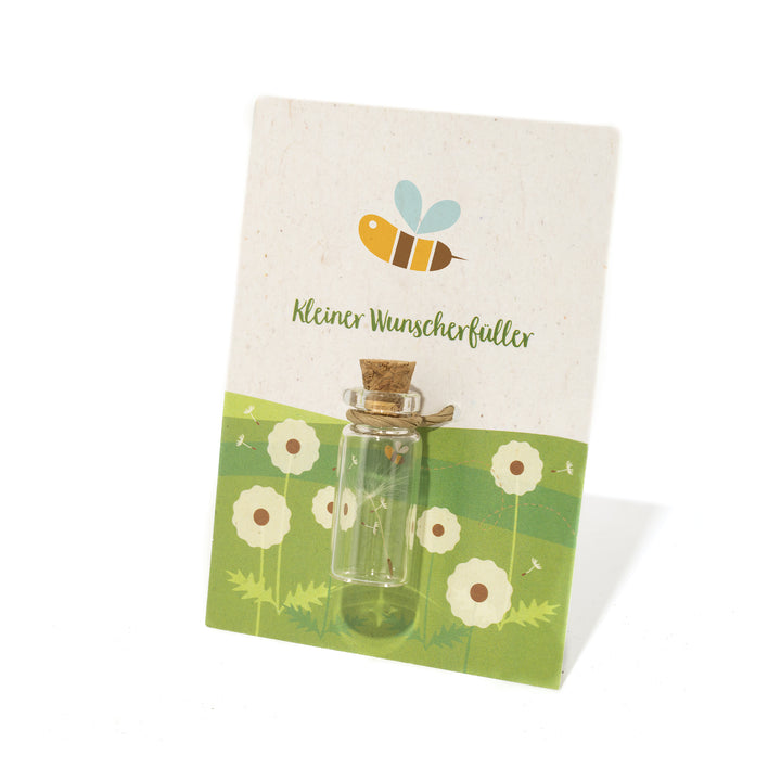 Pequeña botella de cristal con corcho sobre una tarjeta decorativa con motivo de abeja y la inscripción "Pequeño cumplidor de deseos".