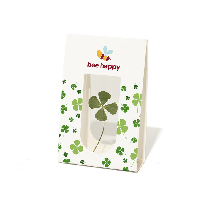 Bolsa de papel con un trébol de cuatro hojas y el texto "bee happy", así como una ilustración de una abeja.