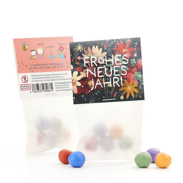 Dos bolsas de bolas de semillas de colores, una con un estampado floral que dice "¡Feliz Año Nuevo!" y otra con descripciones y dibujos, con algunas bolas en el frente.