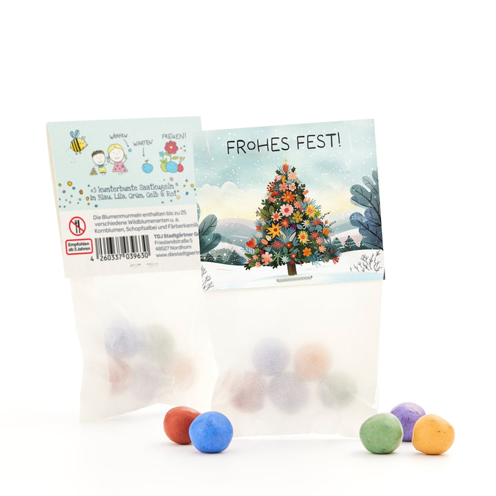 Dos pequeñas bolsas de bolas de semillas de colores, una con un árbol de Navidad y un saludo de "¡Feliz Navidad!", con varias bolas de colores en el frente.