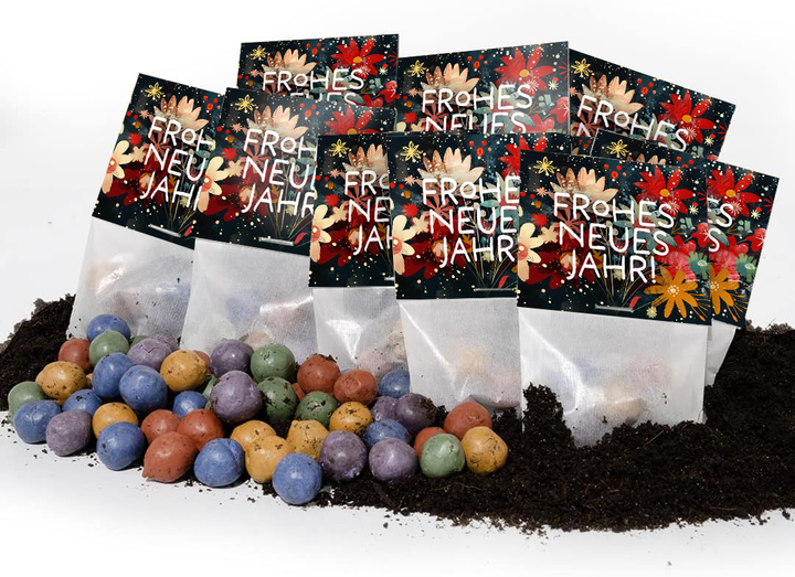 Varias bombas de semillas de colores yacen en el suelo delante de bolsas con la inscripción "Feliz Año Nuevo" y un patrón floral.