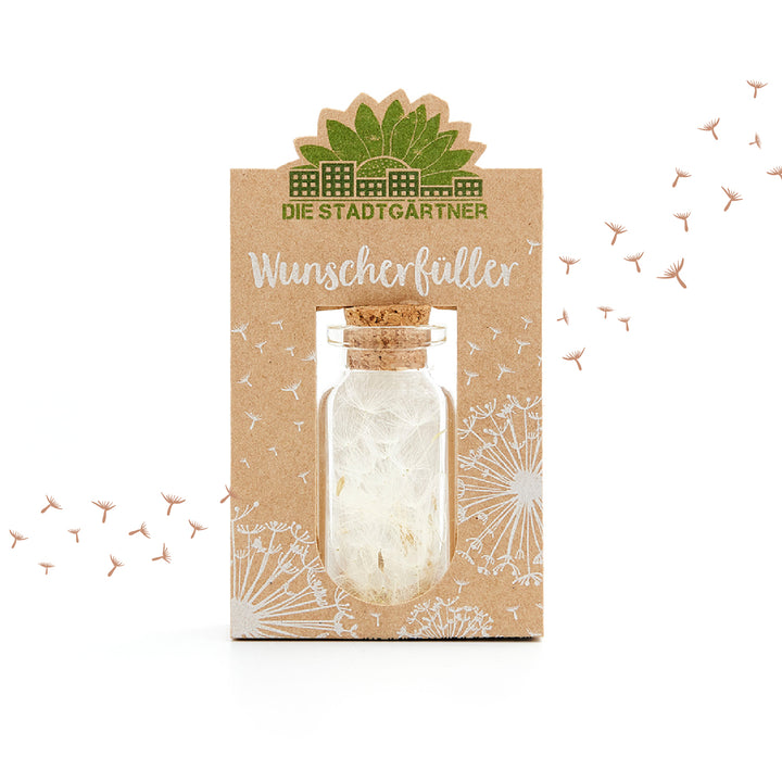 Embalaje del producto 'Wish Fulfiller' con una pequeña botella y semillas de diente de león, rodeadas de un diseño de diente de león blanco sobre un fondo marrón.