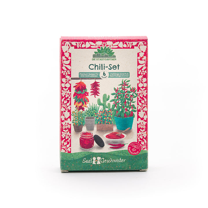 Embalaje de un juego de chile con ilustraciones coloridas de plantas de chile, macetas, chiles y un frasco de chile en polvo, rodeado de un patrón floral rojo.