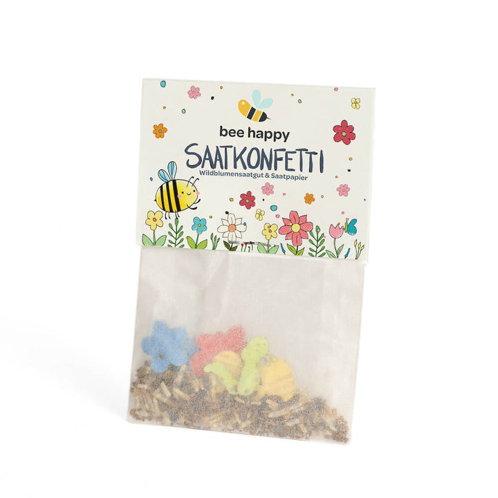 Bolsa con confeti de semillas de colores y la inscripción "bee happy SEED CONFETTI semillas de flores silvestres y papel de semillas", decorada con motivos de abejas y flores.