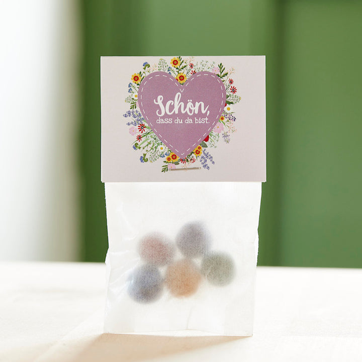 Una bolsa de dulces de colores y una tarjeta con un corazón y la frase "Es genial que estés aquí".