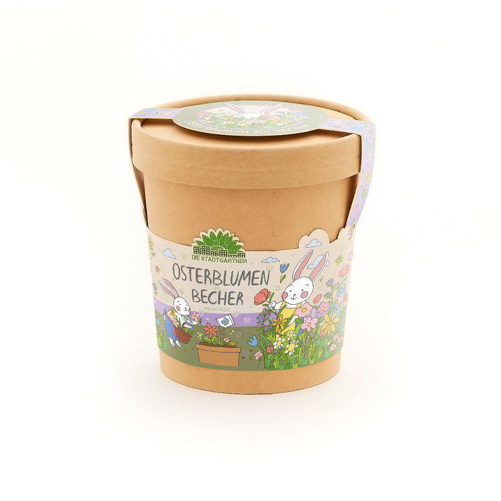 Maceta marrón con coloridas decoraciones de Pascua y la inscripción “Copa de Flores de Pascua”, ilustrada con flores y un conejito.