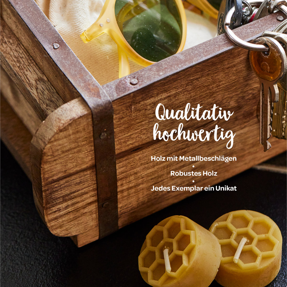 Caja de madera con herrajes metálicos, gafas de sol, un juego de llaves y dos velas de cera de abejas; texto: "Alta calidad: madera con herrajes metálicos, madera robusta, cada pieza es única".